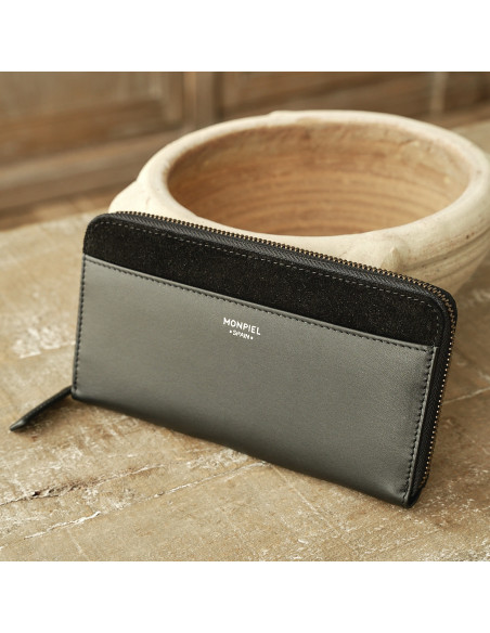 Women’s leather wallet with zipper in black, perspective view resting on ceramic - MONPIEL