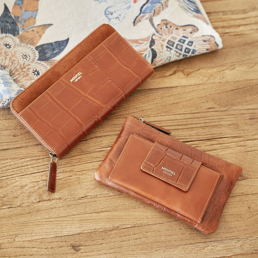 Women's leather zipper wallet in tan, tilted on a wooden table with a magazine - MONPIEL
