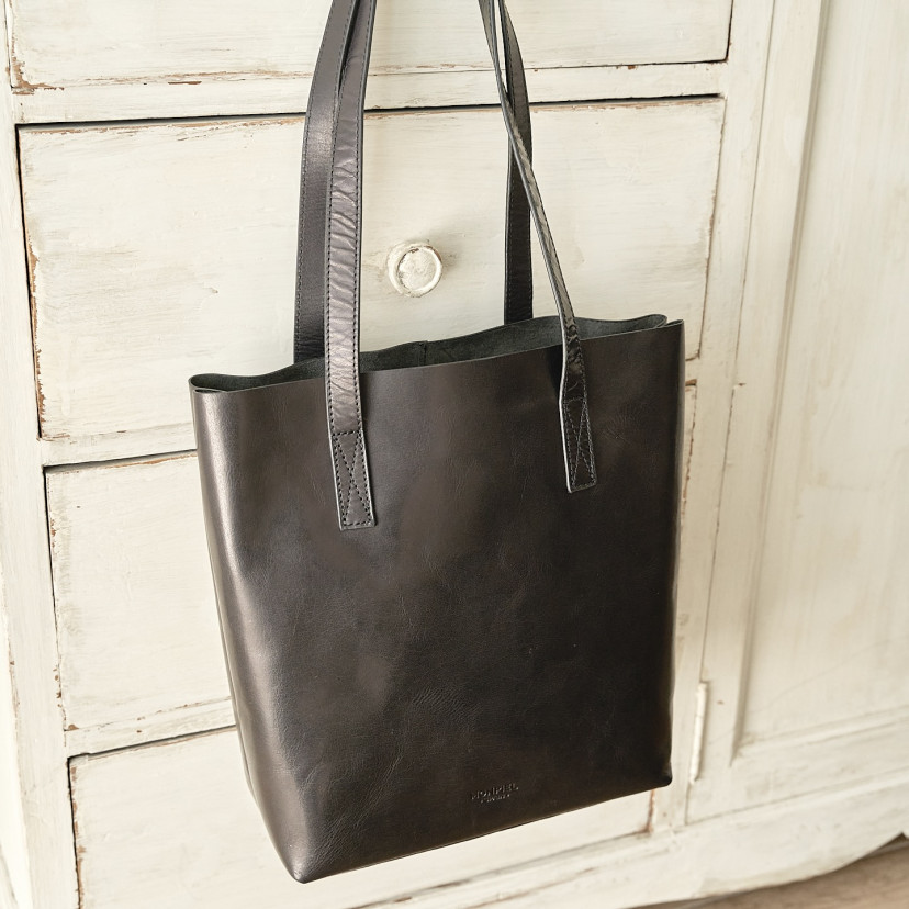 Bolsa shopper de couro na cor preta com vista frontal e pendurada sobre móvel - MONPIEL