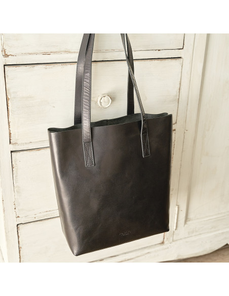 Bolsa shopper de couro na cor preta com vista frontal e pendurada sobre móvel - MONPIEL