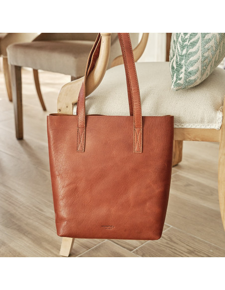 Tan leather shopper bag, shown from the front and hanging on a chair - MONPIEL