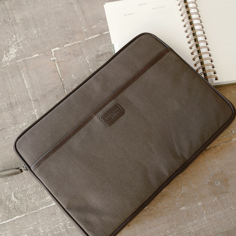 13" and 14"-inch green leather sport laptop sleeve, shown from the front on a wooden table - MONPIEL