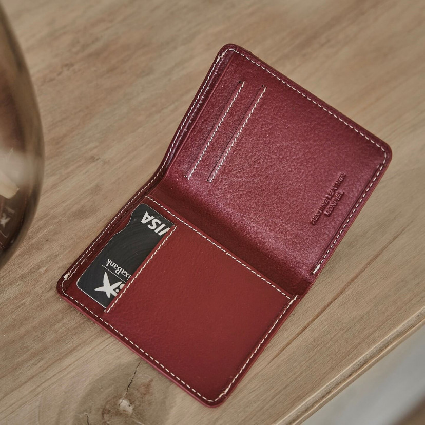 Small burgundy leather men's wallet with billfold, open with card slot details on a table - MONPIEL