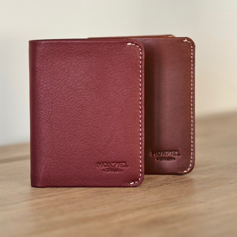 Small burgundy leather men's wallet with billfold, and small Havana leather wallet, resting on a table - MONPIEL
