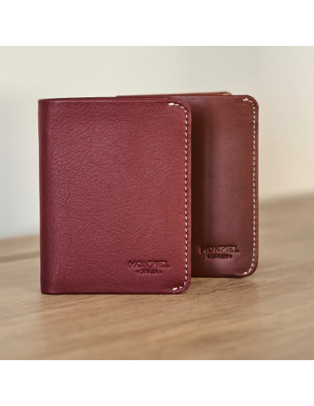Portefeuille pour homme en cuir petit avec porte-billets couleur bordeaux et havane reposant sur une table - MONPIEL