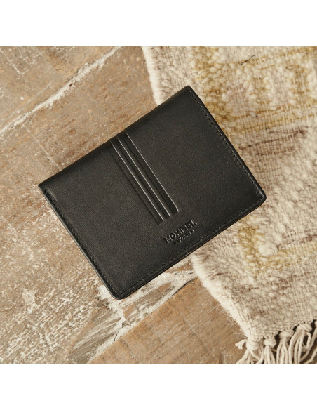 Leather wallet with coin pocket in black with front view resting on the floor and the carpet - MONPIEL Leather wallet with coin pocket in black with front view resting on the floor and the carpet - MONPIEL
