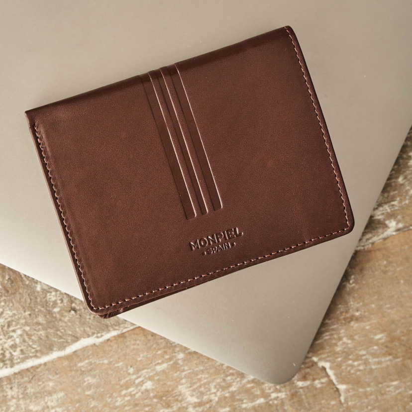 Leather wallet with coin purse in brown, shown from the front resting on a laptop - MONPIEL