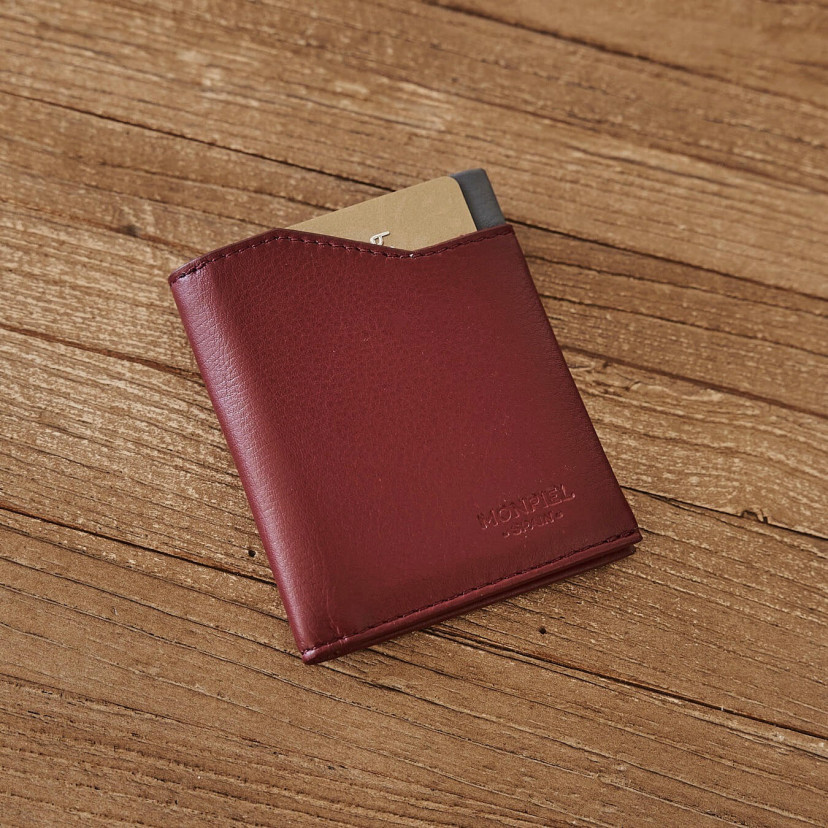Burgundy leather pocket wallet, shown from the front and slightly tilted on a wooden table - MONPIEL