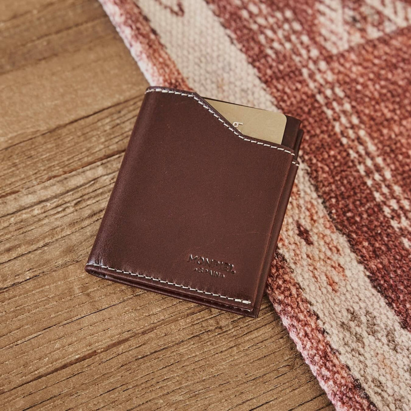 Brown leather pocket wallet, shown from the front and slightly tilted on a wooden table - MONPIEL