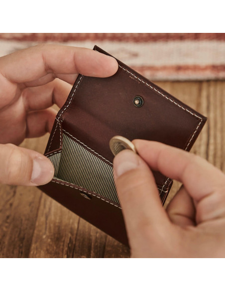 Pocket wallet with coin pocket in leather color, showing detail of inserting a coin - MONPIEL Pocket wallet with coin pocket in leather color, showing detail of inserting a coin - MONPIEL