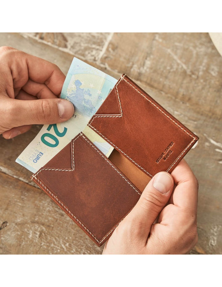 Small Havana leather men's wallet, open and held in hands with a table background - MONPIEL