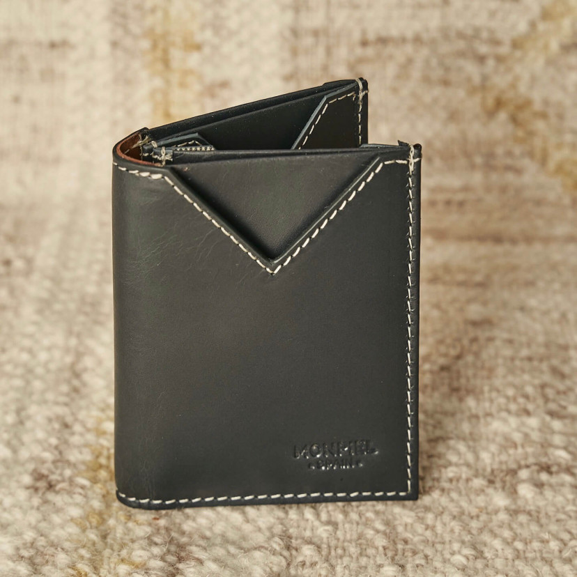 Small blue leather men's wallet, resting vertically semi-open on a carpet - MONPIEL