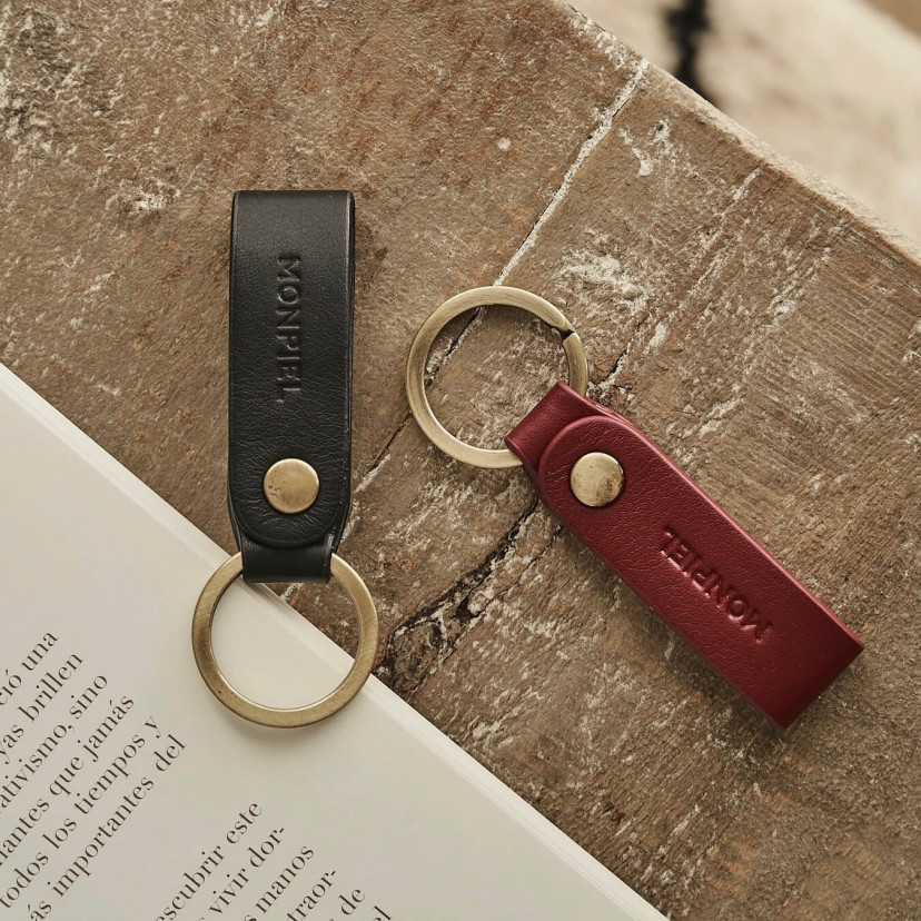 Bordeaux and black bicolor leather pocket keychain, resting on a wooden table - MONPIEL