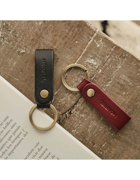 Bordeaux and black bicolor leather pocket keychain, resting on a wooden table - MONPIEL Bordeaux and black bicolor leather pocket keychain, resting on a wooden table - MONPIEL