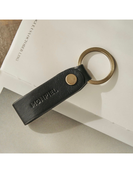 Black bicolor leather pocket keychain, resting on a magazine - MONPIEL Black bicolor leather pocket keychain, resting on a magazine - MONPIEL