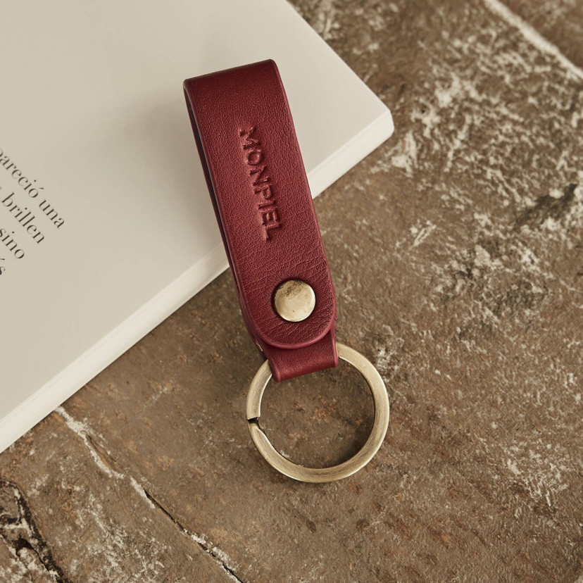 Bordeaux bicolor leather pocket keychain, resting on a magazine and wooden table - MONPIEL