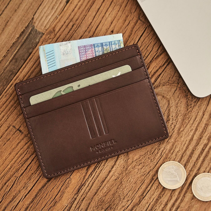 Brown leather cardholder with coin purse, shown from the front with bill and card details, resting on a table - MONPIEL