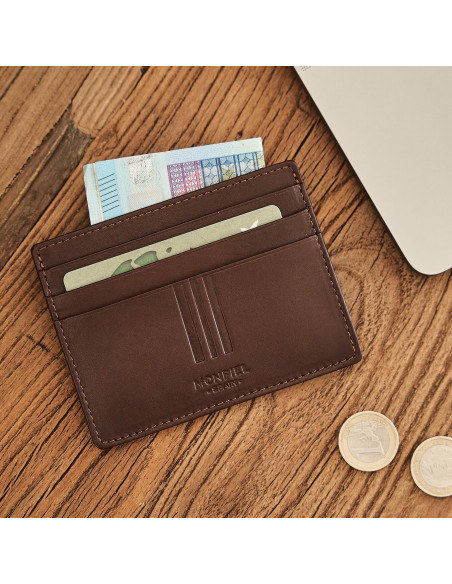 Brown leather cardholder with coin purse, shown from the front with bill and card details, resting on a table - MONPIEL Brown leather cardholder with coin purse, shown from the front with bill and card details, resting on a table - MONPIEL