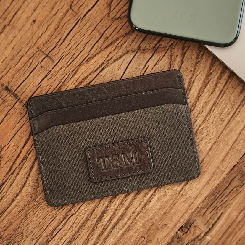 Green sport leather cardholder, shown from the front with personalized detail on a wooden table - MONPIEL