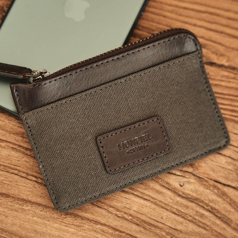Green sport leather coin purse, shown from the front resting on a phone on a wooden table - MONPIEL