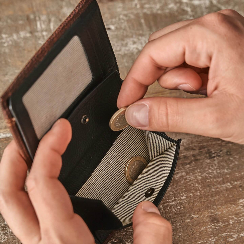 Leather wallet with coin purse inside in black, shown with hands placing coins into the coin purse - MONPIEL