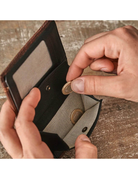 Leather wallet with coin pocket in black, showing hands dropping coins into the coin pocket - MONPIEL
