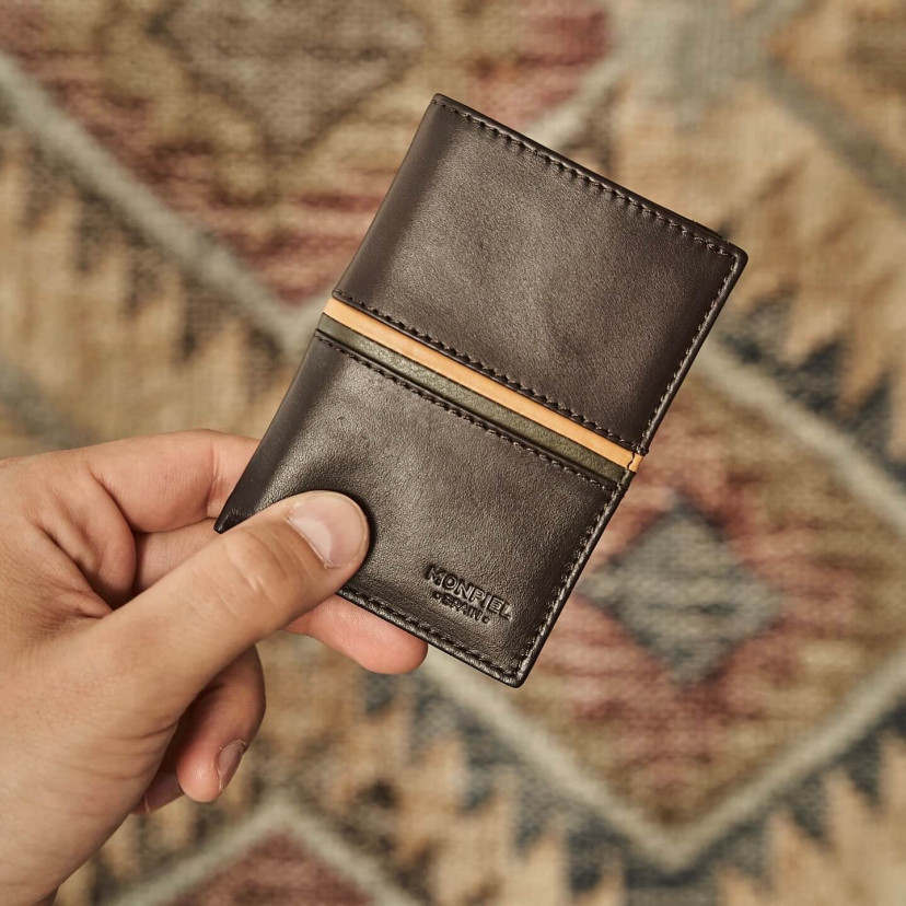 Carteira simples listrada de couro na cor marrom, com vista frontal e fundo desfocado - MONPIEL