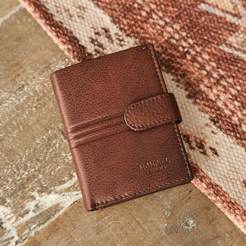 Small leather purse with coin pocket and central clasp in Havana color with a front view on a carpet - MONPIEL