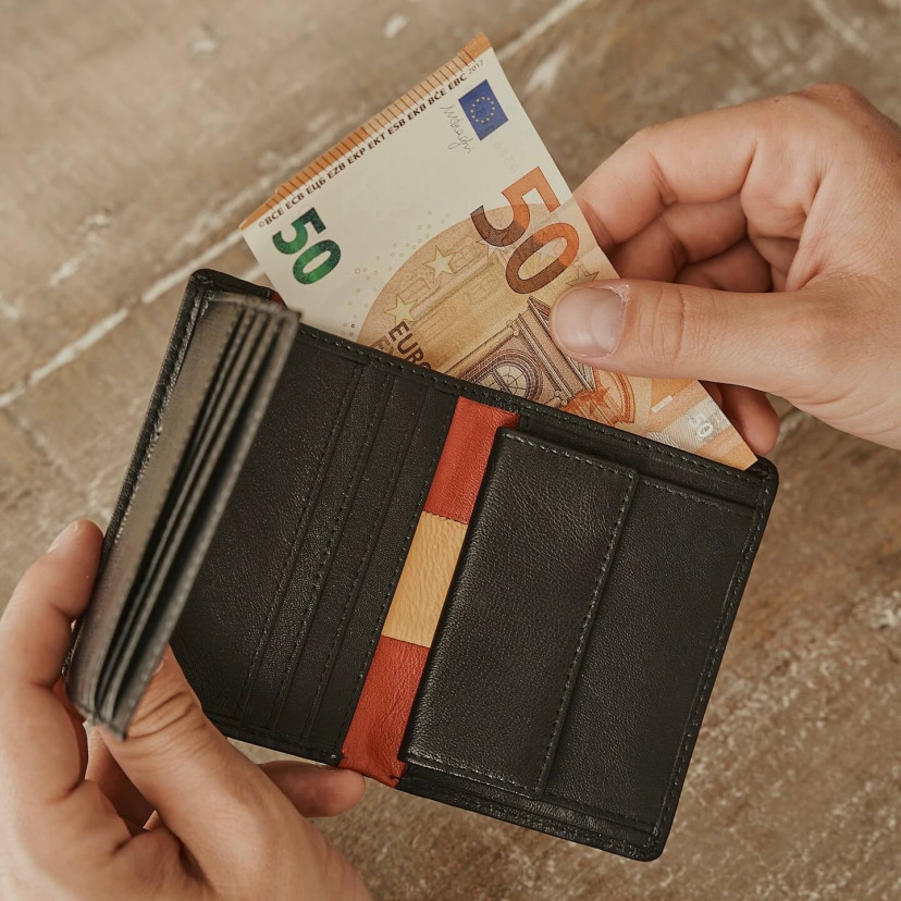Leather wallet with coin pocket, featuring Spanish flag, in black color, open, holding a bill - MONPIEL