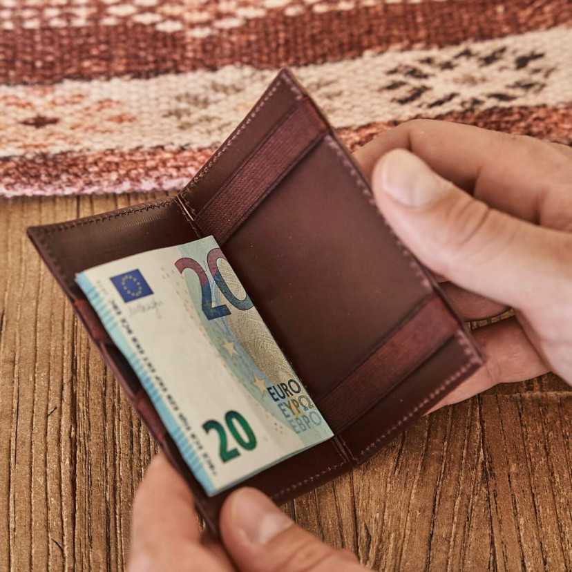 Magic leather card case in Havana color, open with bill detail, on a wooden table - MONPIEL