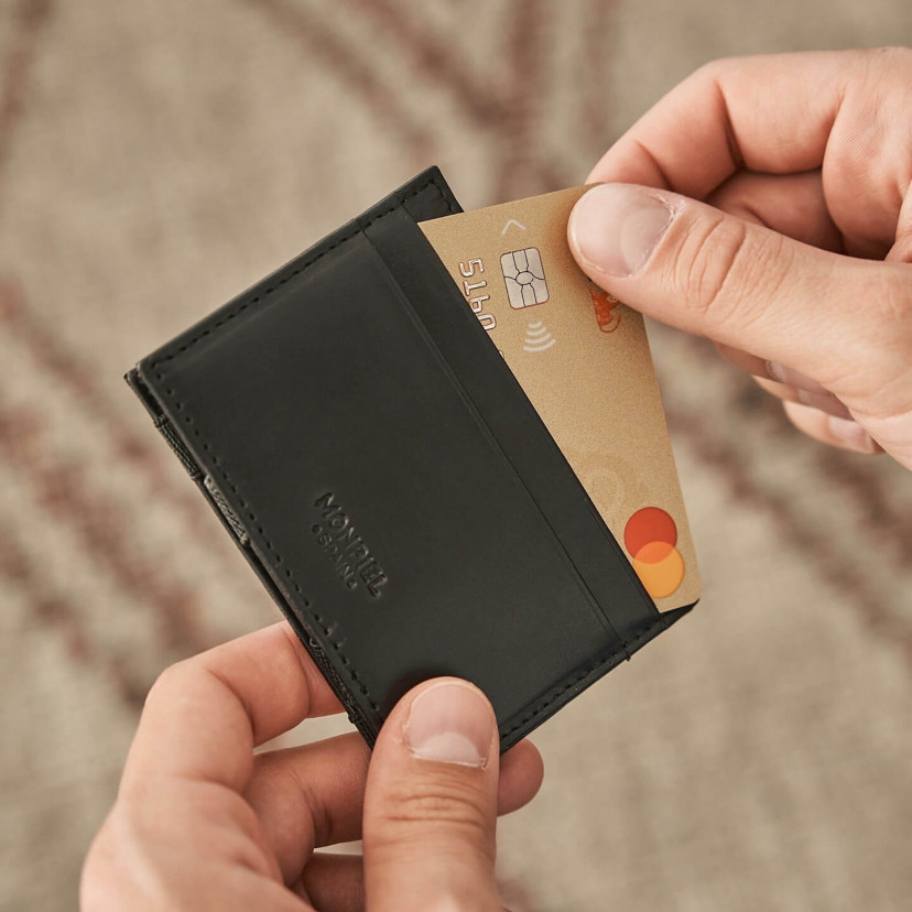 Magic leather cardholder in black color, card slot detail, on a wooden table - MONPIEL