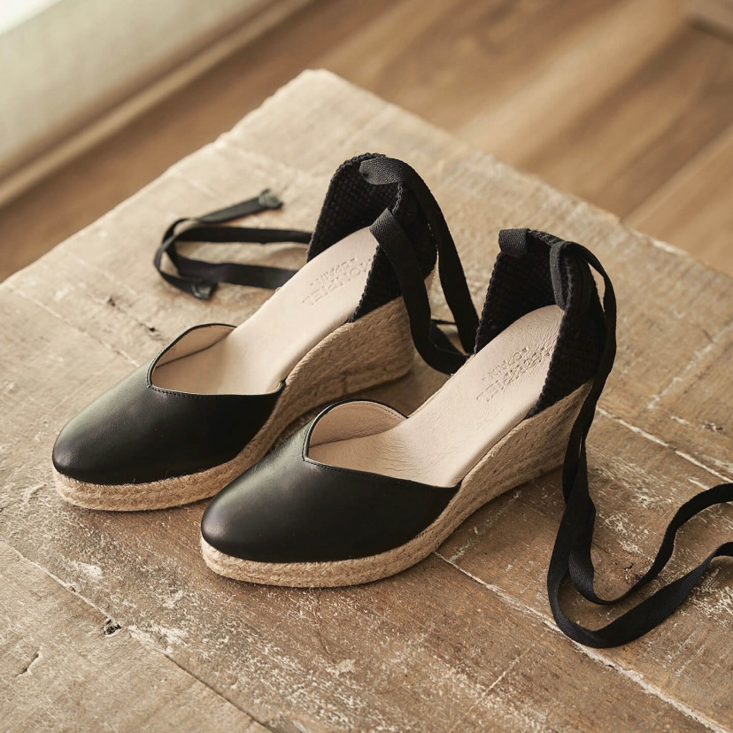 Elba wedge espadrille in black leather, angled view, on a wooden table - MONPIEL