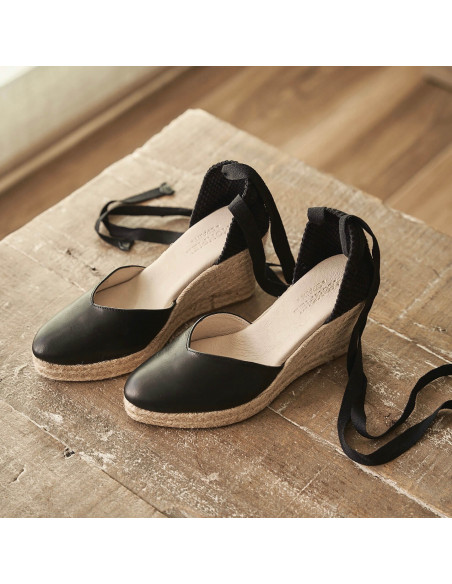 Espadrille à talon compensé Elba en cuir noir, vue en perspective sur une table en bois - MONPIEL