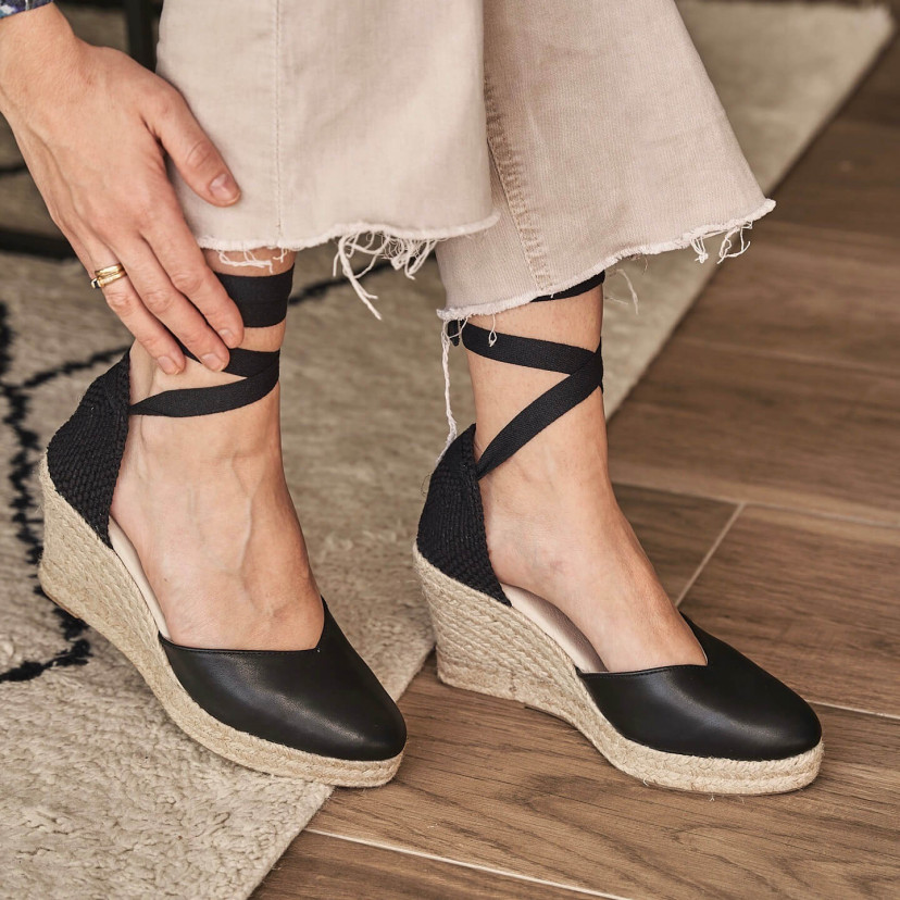 Elba wedge espadrille in black leather, feet on a rug, side profile view - MONPIEL