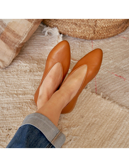 Ballerine plate en cuir couleur cuir, pieds croisés en détail, posés sur un tapis - MONPIEL Ballerine plate en cuir couleur cuir, pieds croisés en détail, posés sur un tapis - MONPIEL