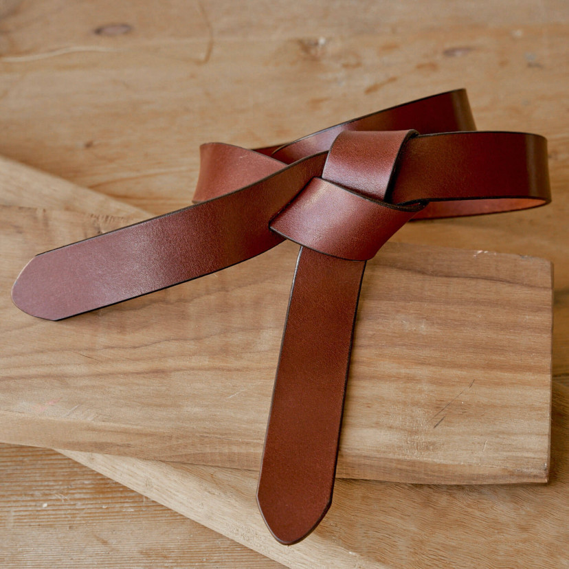 Vaquetilla leather knot belt in tan color, on a wooden table - MONPIEL