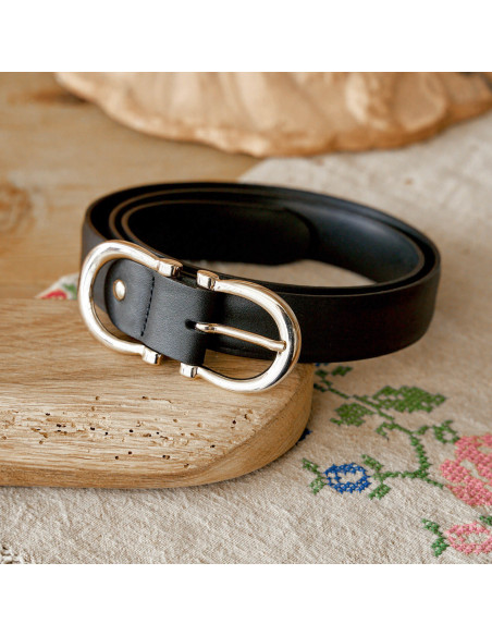 Women’s double buckle leather belt in black, coiled on a wooden board - MONPIEL
