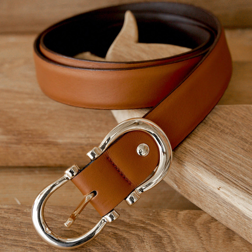 Women’s double buckle leather belt in tan color, coiled on a wooden board - MONPIEL