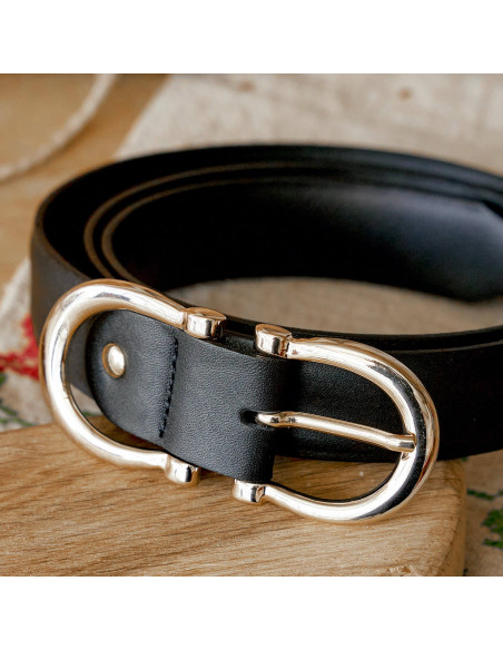 Cintura da donna in pelle con doppia fibbia in colore nero, arrotolata su una tavola di legno con fibbia in primo pian - MONPIEL