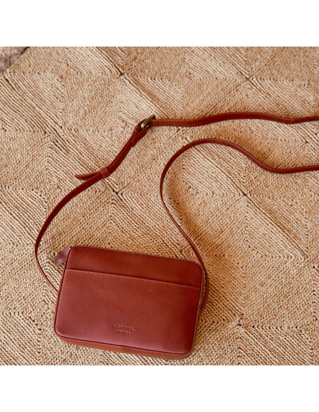 Sac bandoulière en cuir couleur cuir, vue de face avec détail de la sangle réglable sur tapis - MONPIEL Sac bandoulière en cuir couleur cuir, vue de face avec détail de la sangle réglable sur tapis - MONPIEL