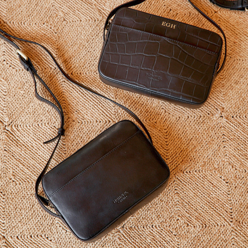 Bolsa tiracolo de couro em preto e coco com vista frontal apoiada sobre tapete - MONPIEL
