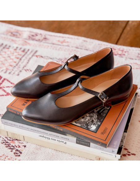 Marieta leather Mary Janes for women in black color, angled view, resting on books - MONPIEL Marieta leather Mary Janes for women in black color, angled view, resting on books - MONPIEL