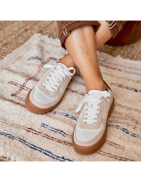 Baskets en cuir Cosmo blanches, pieds croisés sur un tapis, vue de face - MONPIEL Baskets en cuir Cosmo blanches, pieds croisés sur un tapis, vue de face - MONPIEL