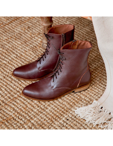 Women’s leather pointed-toe ankle boots in burgundy color, angled view, on a rug - MONPIEL Women’s leather pointed-toe ankle boots in burgundy color, angled view, on a rug - MONPIEL