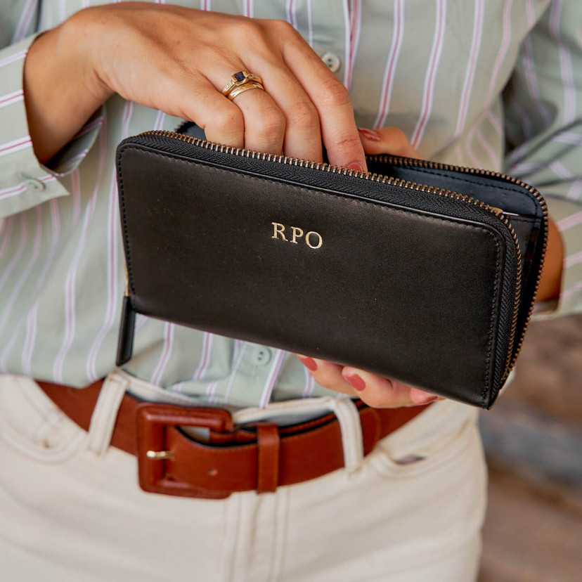 Three gold-embossed initials on a black leather wallet with open zipper - MONPIEL