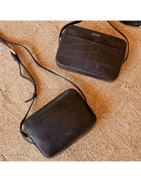 Tre iniziali personalizzate incise in oro su una borsa con stampa cocco nera, accanto a una borsa in pelle nera sempli - MONPIEL