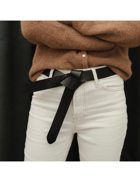 Cinto de couro preto com nó vaquetilla sobre calça jeans branca, vista frontal - MONPIEL Cinto de couro preto com nó vaquetilla sobre calça jeans branca, vista frontal - MONPIEL