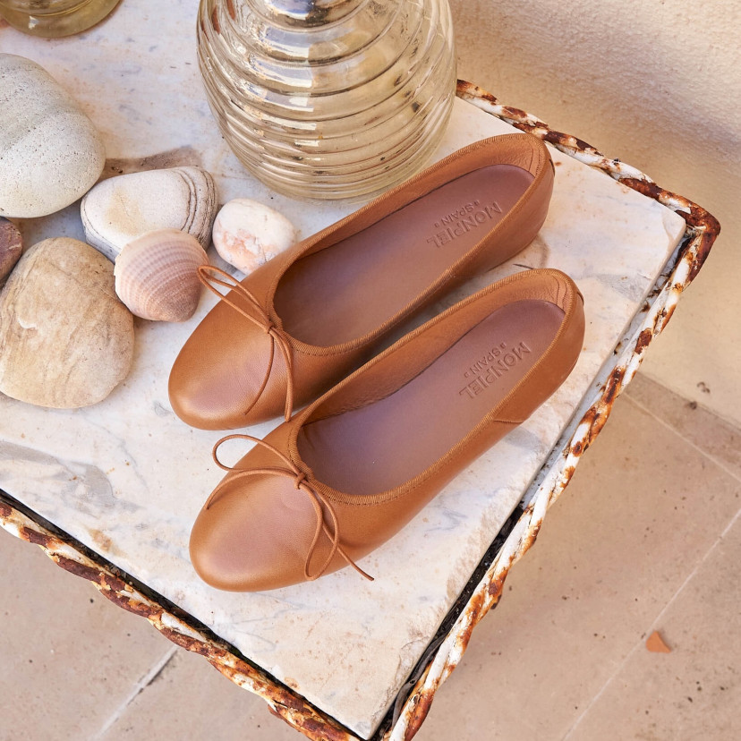 High-cut leather ballerina in tan color, top view, resting on a table next to a vase - MONPIEL