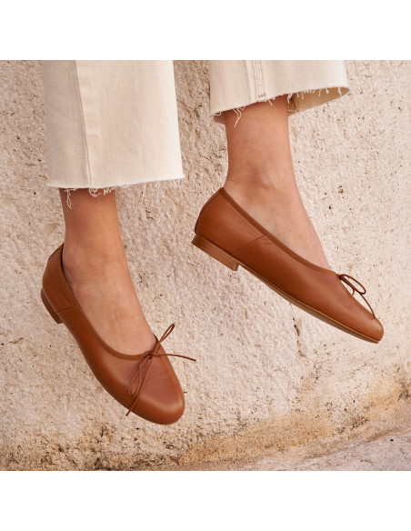 High-cut leather ballerina in tan color, angled view, legs dangling - MONPIEL High-cut leather ballerina in tan color, angled view, legs dangling - MONPIEL