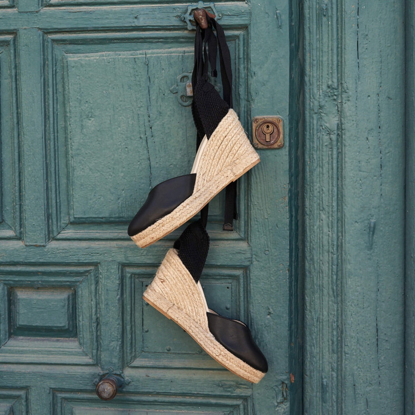 Elba wedge espadrille in black leather hanging over the door handle - MONPIEL